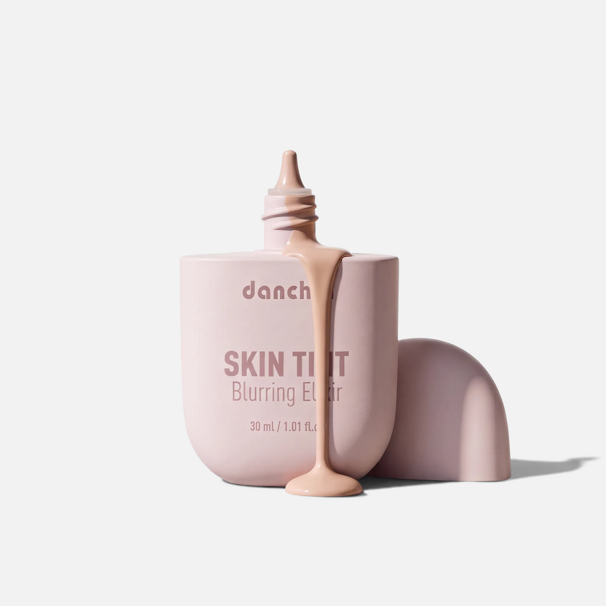 SOLA-GLOW LUME Velvet Foundation in a light pink bottle with liquid formula dripping from the open nozzle